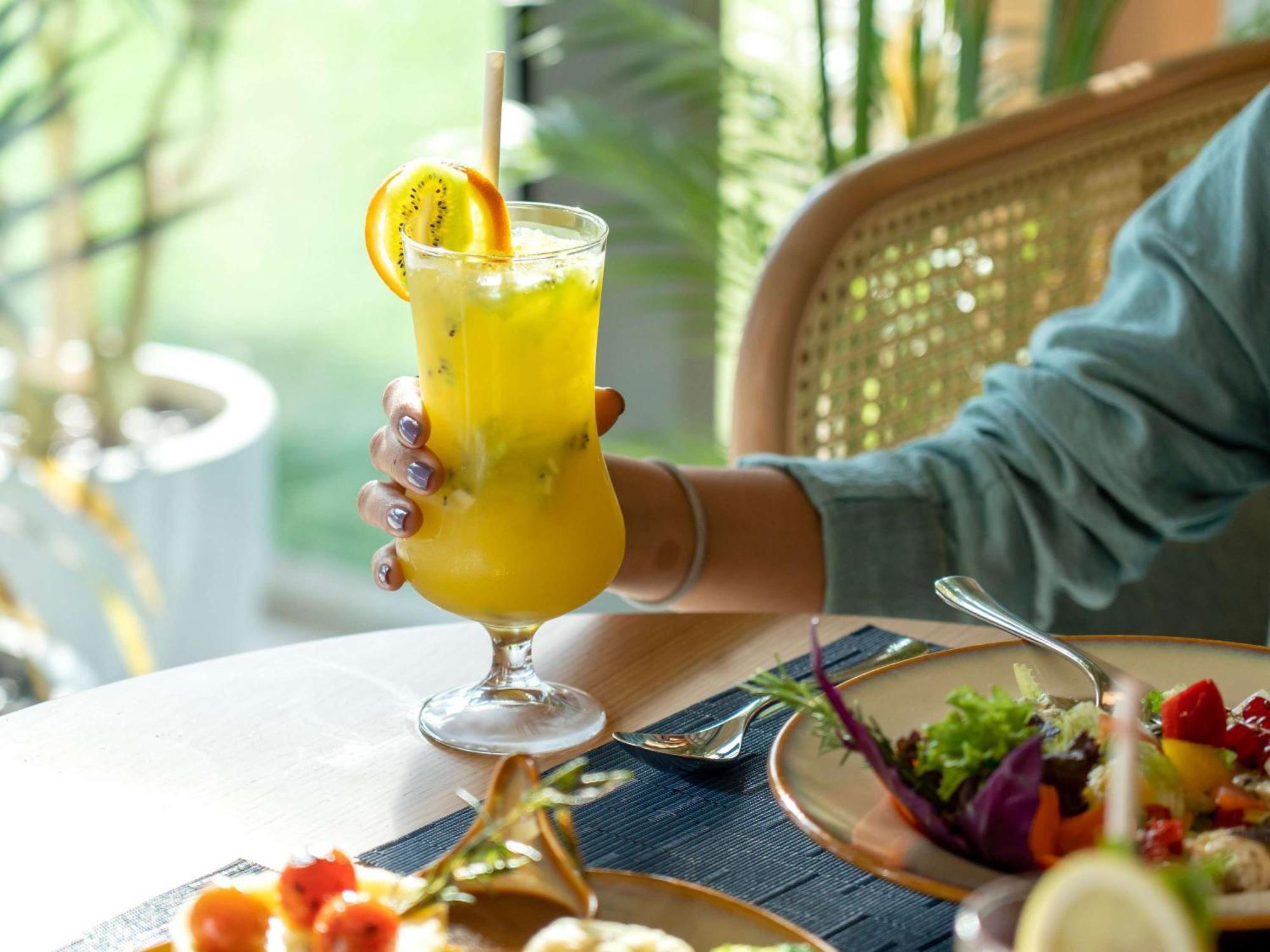 Swissotel Living Jeddah Eksteriør billede A woman holding a glass of juice